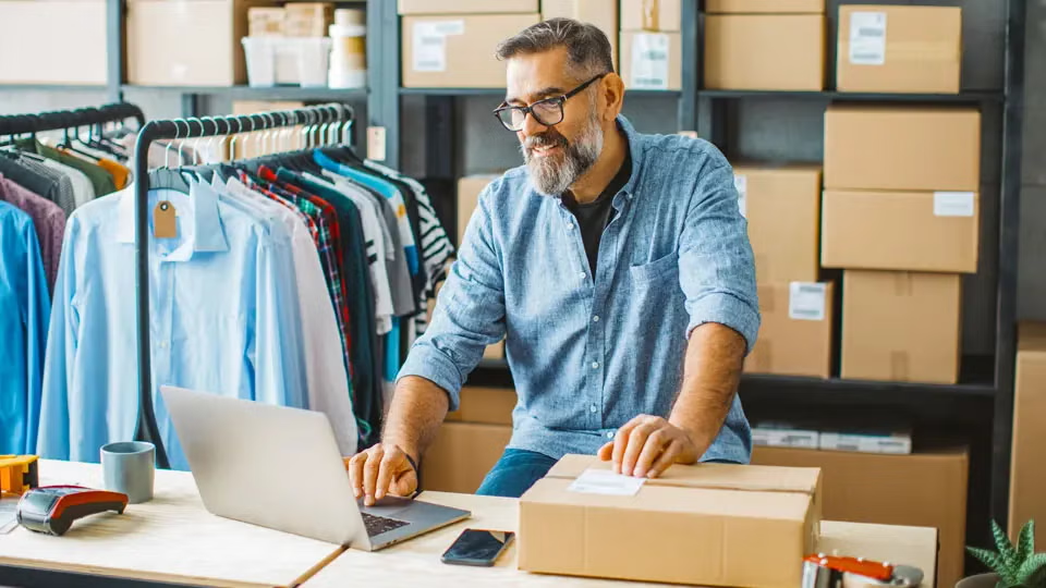 Small business operator preparing marketplace shipments at a desk with packaged orders